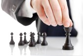 12066752-business-man-moving-chess-figure-with-team-behind--strategy-or-leadership-concept